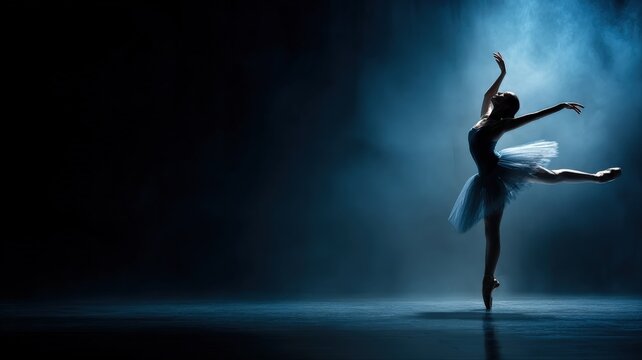 Silhouette of a graceful ballerina performing a delicate arabesque pose en pointe on a dark, moody stage with atmospheric lighting.