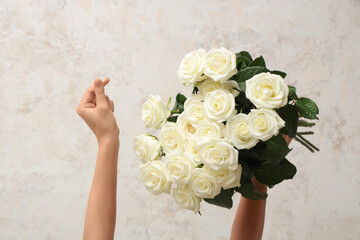 Naklejka premium Woman's hands holding bouquet of beautiful white roses on light background