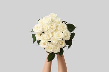 Naklejka premium Hands with bouquet of beautiful white roses on light background