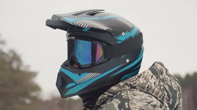 Atv helmet closeup gear inspection, mirrored goggles and textured visor, camo jacket edge, vent and strap details, close lens reflection, maintenance vibe, precise technical focus on materials