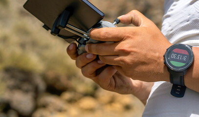 A man is flying a drone, hands hold the remote control. © Zhanna