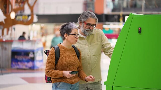 Senior couple withdrawing money from atm machine in public