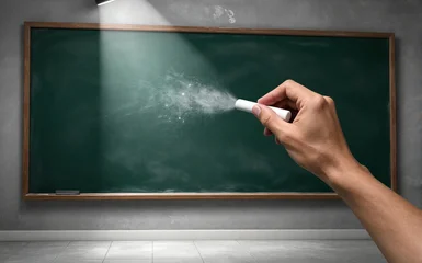 Hand writes on chalkboard under spotlight creating bright dust trail © joeycheung