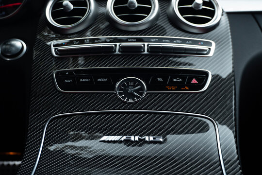 Mercedes AMG C63 carbon fiber center console logo and analog IWC watch, Luxury sportscar cabin details and controls