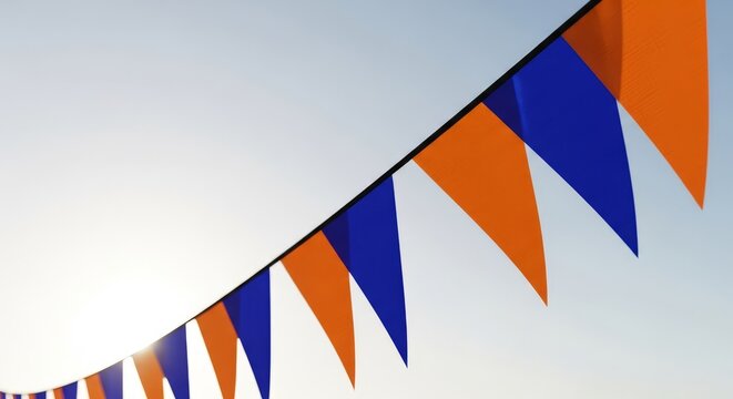 A detailed close-up of triangular bunting flags in bold orange and deep blue, creating a striking complementary color contrast against a clear sky, aesthetic, festival, orange