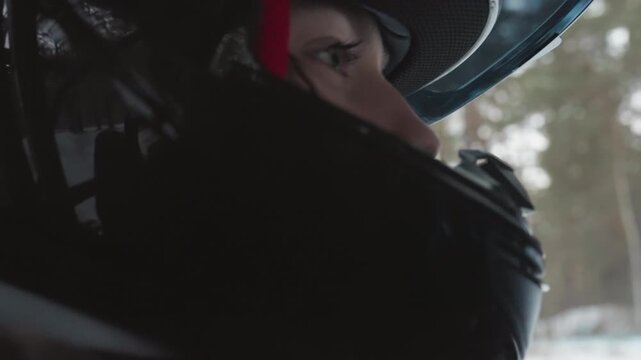 Helmeted rider in snowy forest eyes fixed on trail, visor closeup showing concentrated gaze and breath in cold air, protective gear and gloves visible, offroad terrain under pine canopy, tense