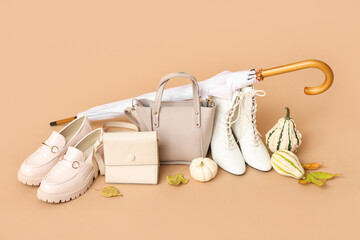 Different white shoes with stylish bags, umbrella, pumpkins and autumn leaves on brown background © Pixel-Shot