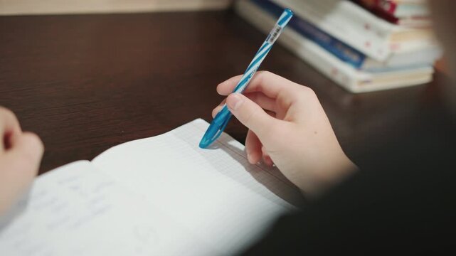 Desk surface with notebook and pen, grandson writes notes with steady hand, closeup on handwriting and page texture, stacked books and soft light in background, focused study atmosphere