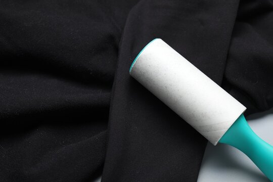 Lint roller and clothes on grey background, closeup