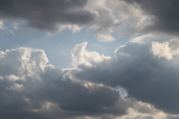 Fototapeta premium Sky with sunlight. Sunshine piercing through cloudy sky. Cloudfilled sky illuminated by scattered sunbeams. Overcast sky with bright rays breaking through heavy clouds
