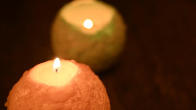 木のテーブルの上で炎が揺れる丸いキャンドル。