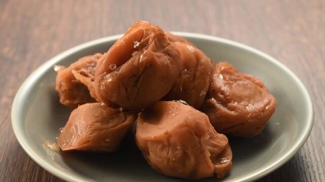白い皿に盛られた梅干しのクローズアップ動画　日本の伝統的な塩漬け梅の食品素材