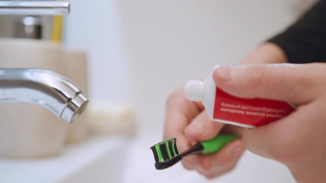 Hands brushing teeth. Playful scene of brushing teeth properly demonstrated. Interactive moment showcasing how to properly apply toothpaste to toothbrush in cheerful bathroom environment