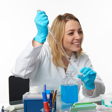 Woman european female scientist using serological pipette transferring blue solution in laboratory