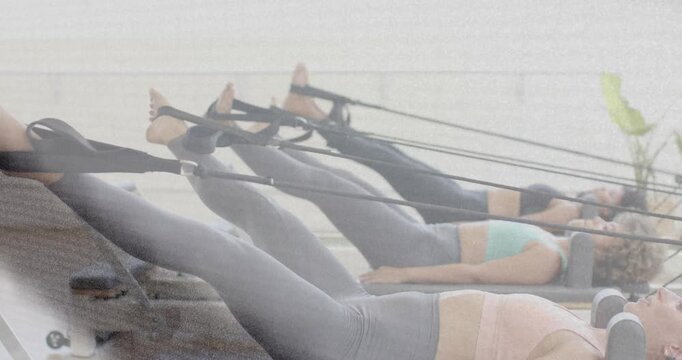 Vertical video: Lifting three women in leggings raising legs on reformers after class cue in studio