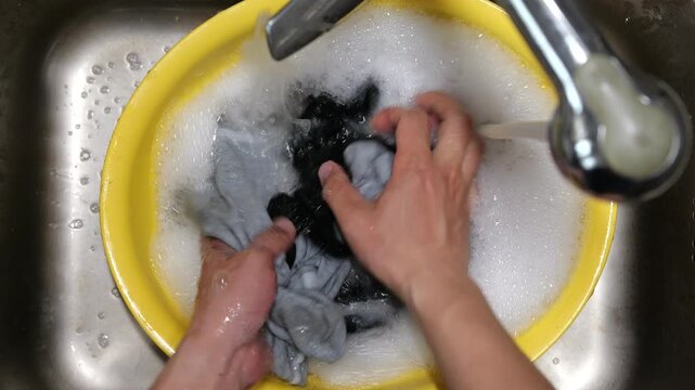 Hand-washing socks in a basin with bare hands.