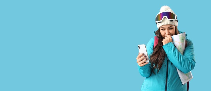 Troubled female guide with map using mobile phone on light blue background with space for text