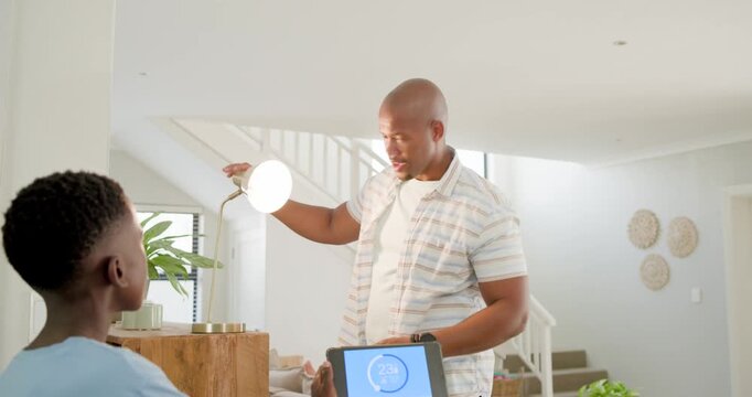 Son raising tablet triggers dad coming, leaning and gesturing to view screen while son explaining