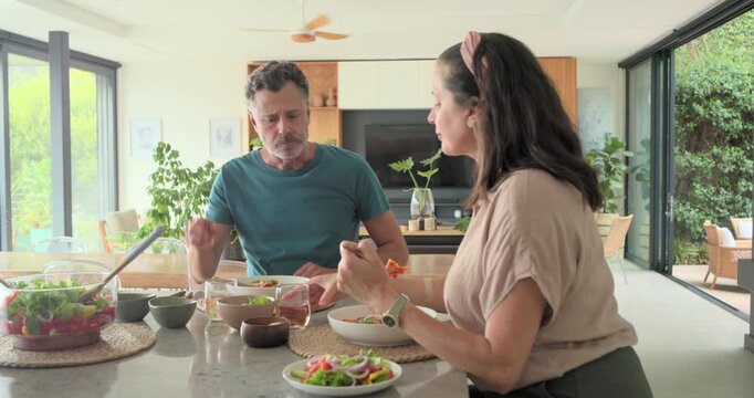 Woman serving salad sharing meal, man tasting, toasting glass, food icons rising over marble island