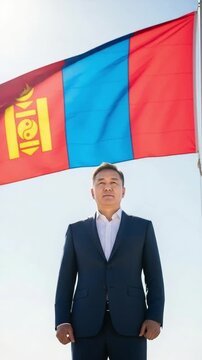 Mature Mongolian diplomat in formal suit posing with national flag outdoors