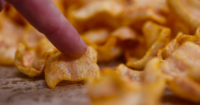 crispy mashed potato chips fried in a large amount of sunflower oil, sprinkled with red hot pepper spices, delicious high-calorie chips with spices are scattered on the table