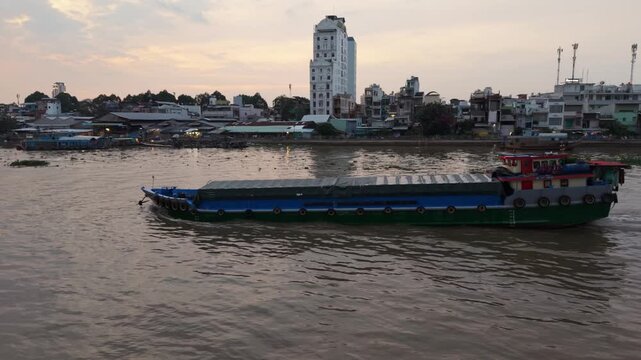 Inspectors Observe Cargo Vessel Navigating Can Tho During Sunset Hours. Closeup View Of Freight Ship Moving Along Can Tho River At Sunset With Dock Inspector Watching Cargo Transfer
