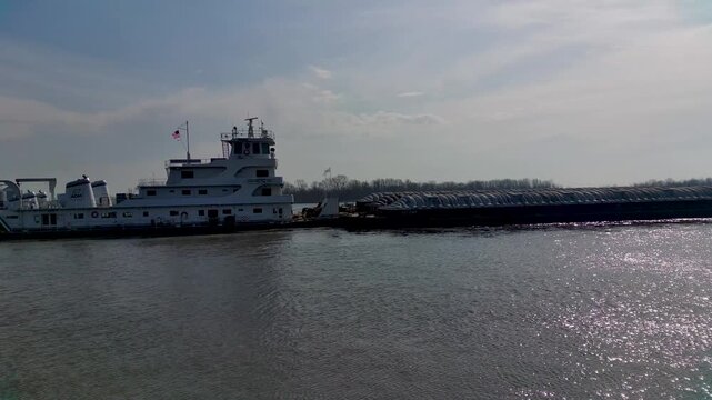 Tugboat pushing heavy industrial barges on the Mississippi River near rural Midwest town