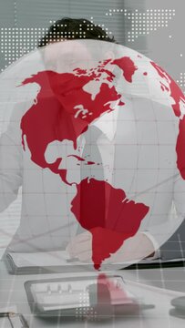 Vertical video: Business team signing deal at table faint globe rotating and revealing fist bumping