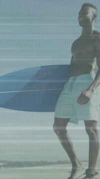 Vertical video: Spotting waves, surfer walking beach holding blue surfboard preparing to surf