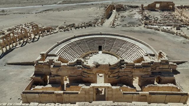 Cinematic aerial view of the remarkably preserved Roman Theatre in the archaeological site of Palmyra