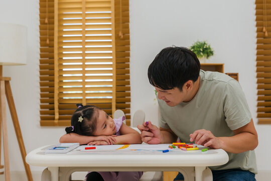Caption/Description: father and child girl drawing and painting with colorful oil pastels on paper
