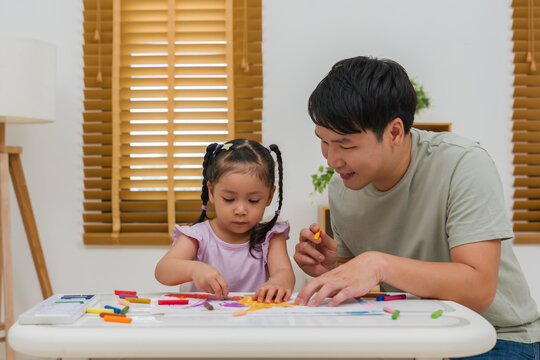 Caption/Description: father and child girl drawing and painting with colorful oil pastels on paper