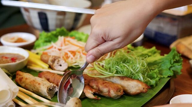 Hand Cutting Grilled Pork Skewers Nem Nuong with a Metal Spoon