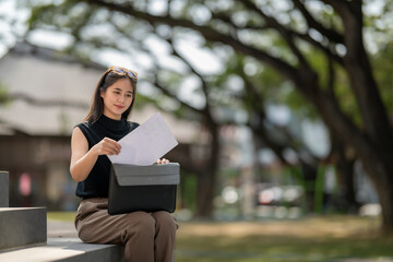 Fototapeta premium Woman placing documents into messenger bag outdoors