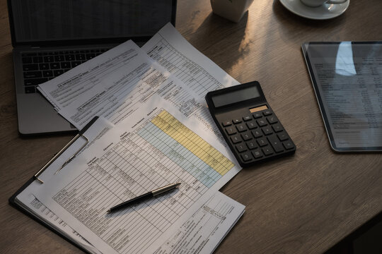 Financial documents and spreadsheet with calculator on desk during budgeting and accounting process for expense calculation, financial analysis, report preparation, and cost management in office works