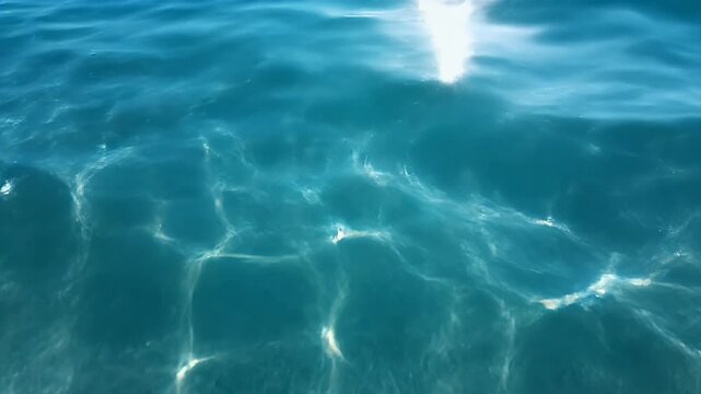 Sunlight dances on the surface of clear turquoise water, creating a mesmerizing pattern of light and shadow.