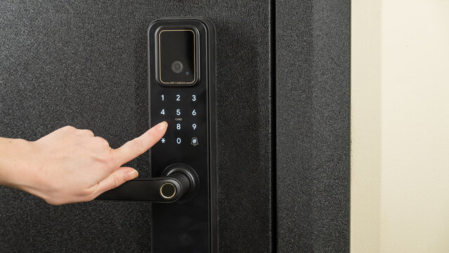 A woman opens a modern smart door lock with a digital keypad using a code.
