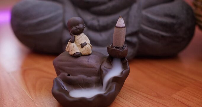 Aromatherapy smoke. Meditation figurine. Fume waterfall stream down in holder with baby monk statue during spiritual yoga session.