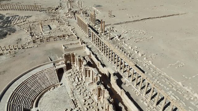 Cinematic aerial drone shot of the historic Roman Theatre in Palmyra, a UNESCO World Heritage site in the Syrian desert