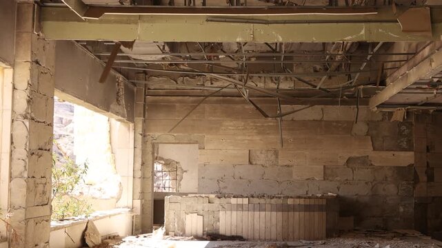 Detailed interior shot of a war-torn room in Ma'aloula, featuring shattered windows, debris, and concrete rubble