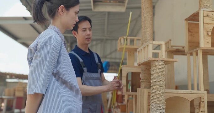 Entrepreneur and carpenter review wooden furniture mockup and prototype pieces, discuss design details and inspect quality at a small business workshop during product development.
