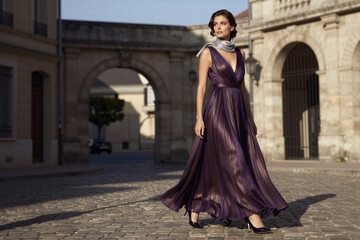 Naklejka premium Woman walking in flowing dress on cobblestone street plaza