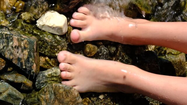 Teenager girl relaxing in water, barefoot in clear cool water. Healthy lifestyle. Young woman enjoying nature on the beach. Ripple patterns reflect light on water over pebbles