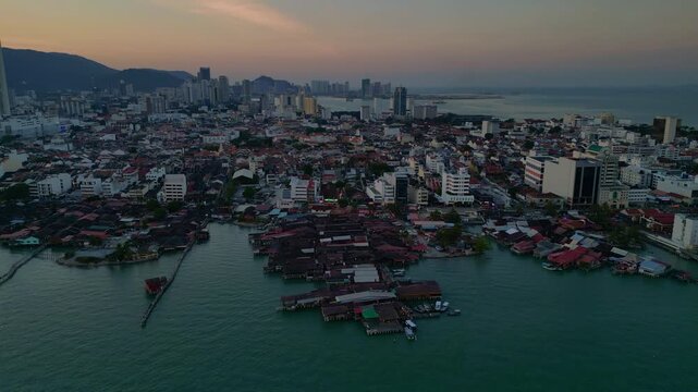 historic wooden clan jetties and waterfront homes contrasting modern skyline and hills in George Town, Penang, Malaysia. Wonderful aerial view panorama overview drone