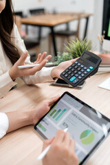 Businesswoman using calculator and tablet to analyze CSR and financial reports, professional accounting and sustainability concept.