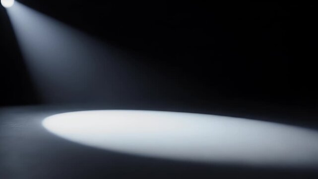 A dramatic spotlight illuminates dust particles suspended in a dark, abstract space, creating a captivating visual effect.