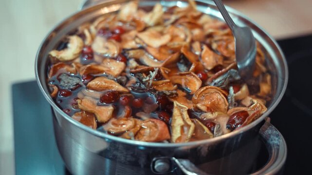 Closeup Stirring Spiced Fruit Compote, Caucasian Hands Mixing Apple Slices, Cranberries And Orange Zest In Stainless Pot, Glossy Bubbling Syrup,