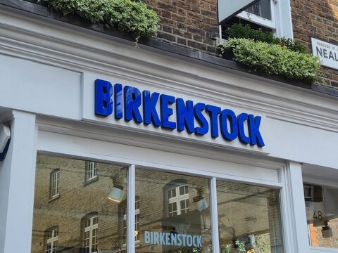 London, UK 03.07.2025 Birkenstock store facade with blue brand signage above shop window in urban street retail setting with reflections of historic buildings