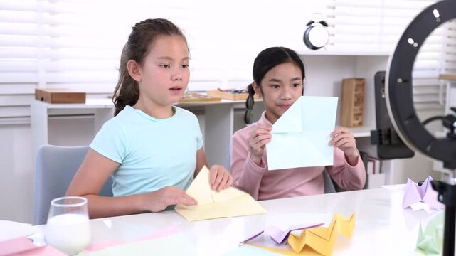 Modern young students online learning content creator, elementary girls explain homework to teacher record paper activity by phone, digital education, creativity vlog, alpha generation study children