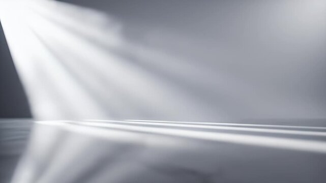 A minimalist grayscale image showcases a dramatic interplay of light and shadow across a smooth, undefined surface, creating an abstract and serene visual experience.